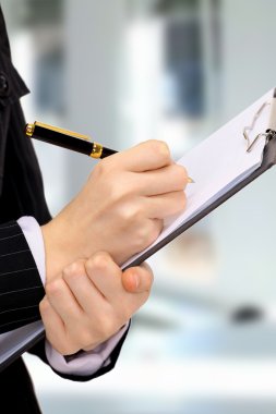 Close-up of business person hand with pen over document clipart