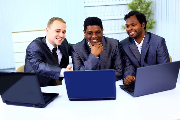 Міжрасовий бізнес команда працює на ноутбуці в сучасному офісі — стокове фото