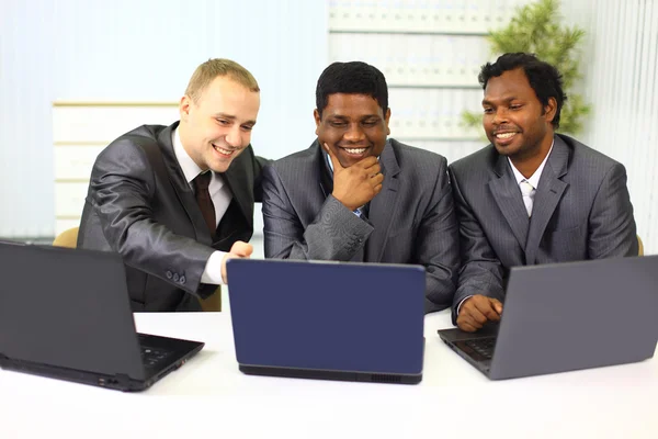 在现代办公室的笔记本电脑上工作的跨种族商业团队 — 图库照片