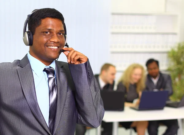 Portrait d'un homme d'affaires souriant avec des écouteurs dans un centre d'appels — Photo