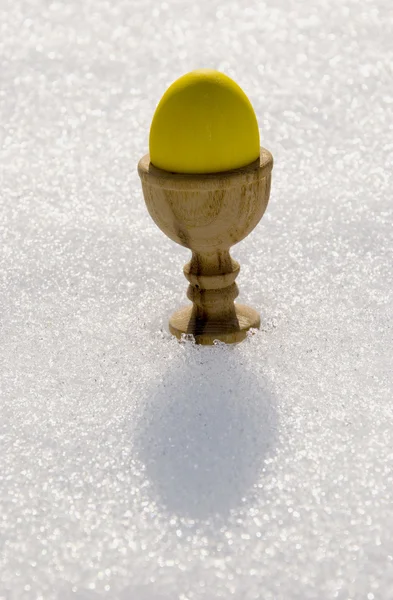 Ovo de Páscoa amarelo na neve de primavera — Fotografia de Stock