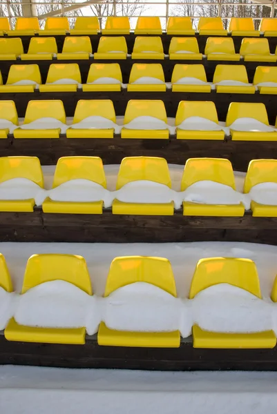 Трибуна футбольного стадиона желтые стулья и снег — стоковое фото
