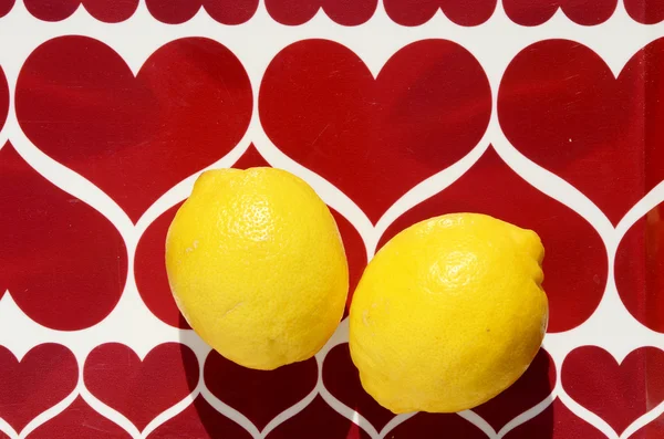 Twee gele citroenen op hart achtergrond — Stockfoto