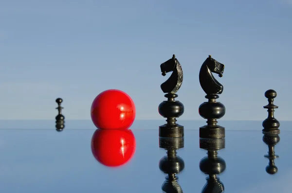 Zwarte chessmans op spiegel en rode bal — Stockfoto