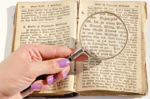 Altes religiöses Buch und Hand mit Handglas — Stockfoto