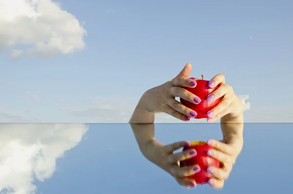 Mãos com maçã vermelha e espelho — Fotografia de Stock