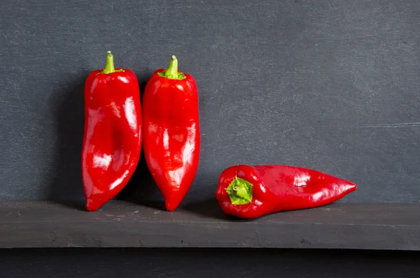 Drie rode pepers op zwart — Stockfoto