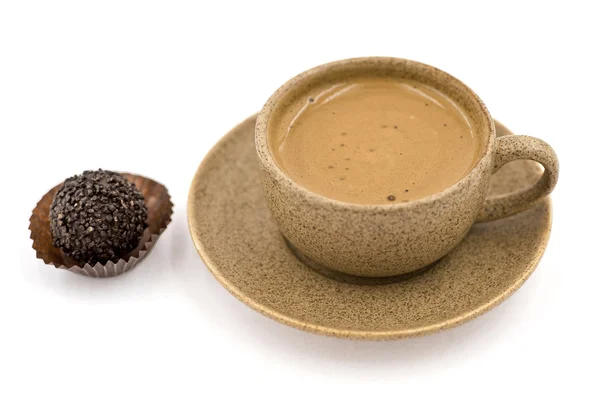 Una tazza con caffè Accanto a una caramella sullo sfondo bianco — Foto Stock