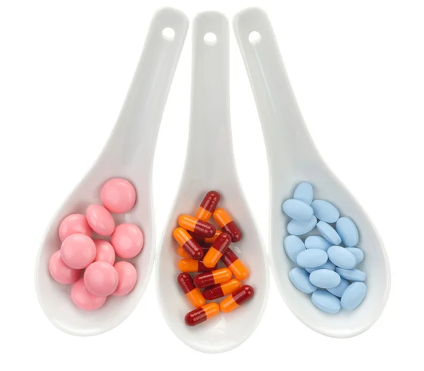 Three ceramic spoons with colorful pills — Stock Photo, Image