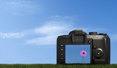 Digital camera on grass against blue sky clipart