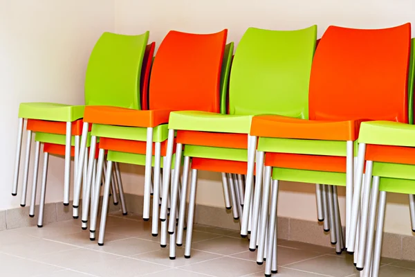 Cadeiras coloridas para os visitantes empilhados uns nos outros e classificados — Fotografia de Stock