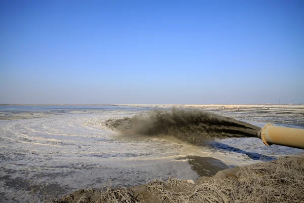 Soplando arena hecha ingeniería de tierra junto al mar Fotos de stock