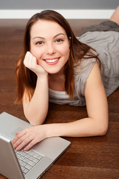 Ευτυχισμένη γυναίκα με φορητό υπολογιστή που βρίσκεται στον όροφο — Φωτογραφία Αρχείου