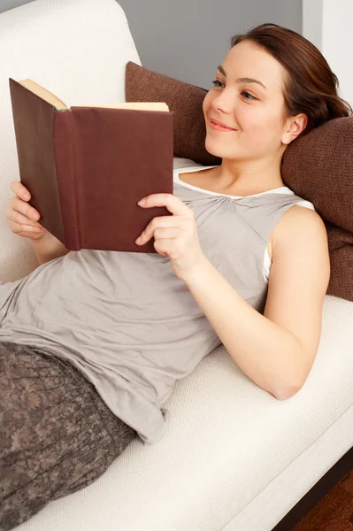 Kobieta z książki leżące na kanapie — Zdjęcie stockowe