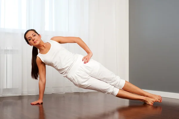 Mladá žena cvičí jógu v místnosti — Stock fotografie