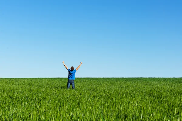 Счастливый человек стоит на зеленом лугу — стоковое фото