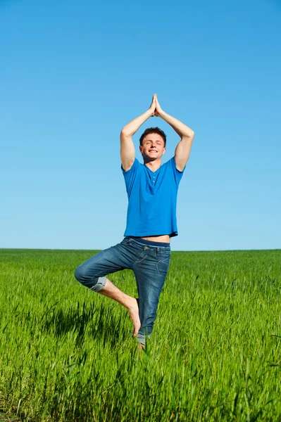 Gökyüzüne karşı yoga yaparken sağlıklı genç adam — Stok fotoğraf