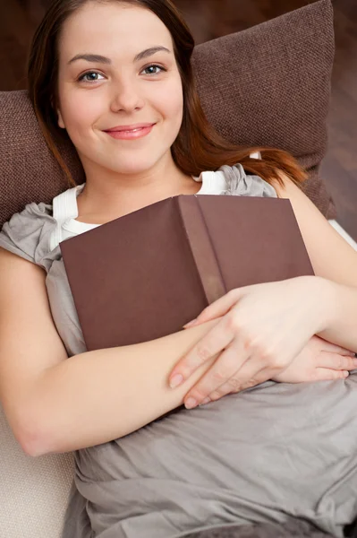 Frau mit Buch auf Sofa liegend — Stockfoto