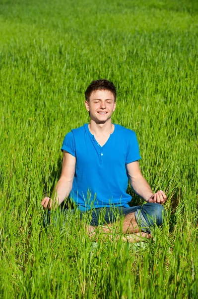 Medytacja młody człowiek na zielonej trawie — Zdjęcie stockowe