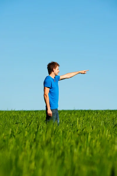 Man står i det gröna fältet och pekar — Stockfoto