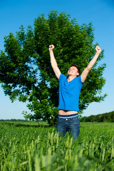 Hombre feliz contra el árbol y el cielo azul —  Fotos de Stock