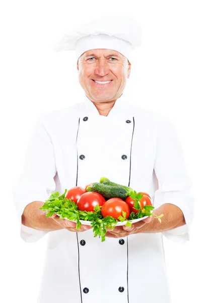 Happy chef holding plate with vegetables — Stock Photo, Image