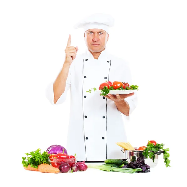 Серьезный повар держит тарелку с овощами — стоковое фото