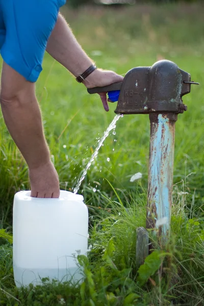 Az ember gyűjt a víz a régi vízpumpa — Stock Fotó