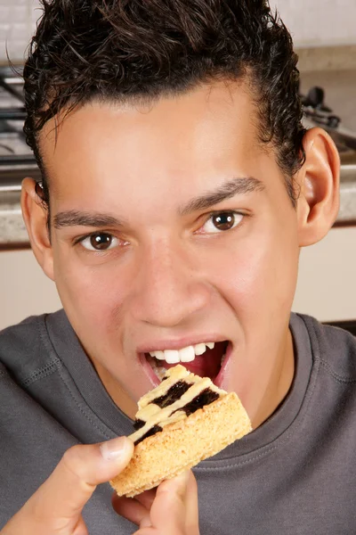 Jeune homme mangeant tarte aux fruits — Photo