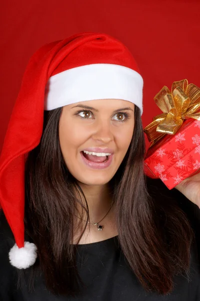 Santa Claus girl shaking Christmas present — Stock Photo, Image