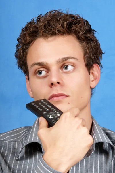 Pondering young man with remote control — Stock Photo, Image