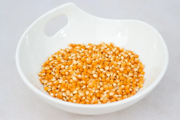 Pile de graines de maïs soufflé isolées sur un bol blanc — Photo