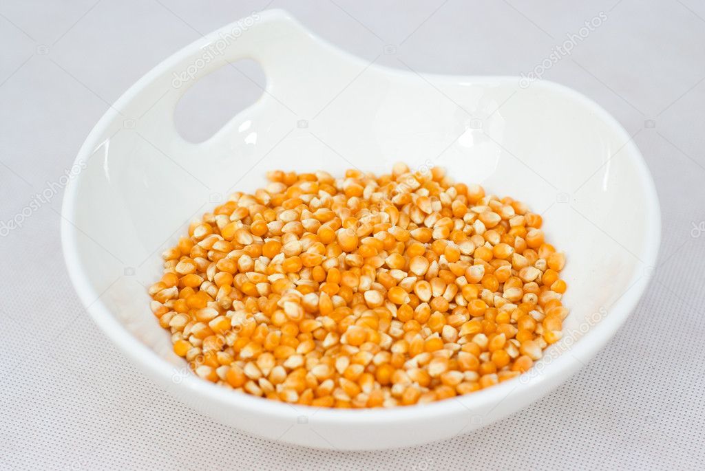 Pile of popcorn seeds isolated on white bowl — Stock Photo © aletrac