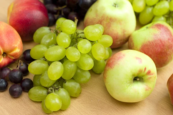 Świeżych owoców, jabłka, winogron i brzoskwinie na stole — Zdjęcie stockowe