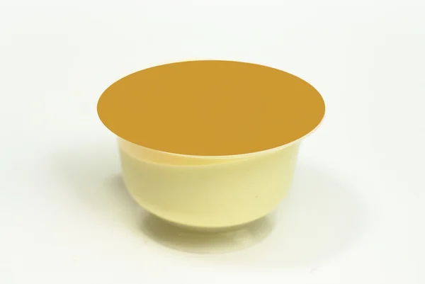 Пачка ванильного крема с карамельным десертом на белом — стоковое фото