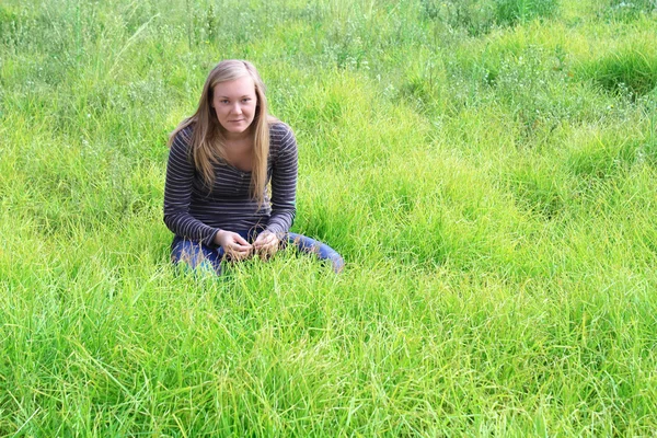 Dívka sedící v trávě. — Stock fotografie