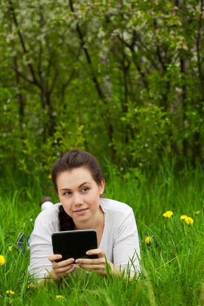Dívka s ebook ležící na trávě — Stock fotografie