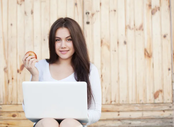 Chica sonriente con portátil y manzana — Foto de Stock