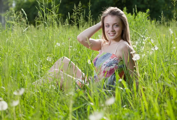 Szczęśliwa dziewczyna siedzi w trawie — Zdjęcie stockowe
