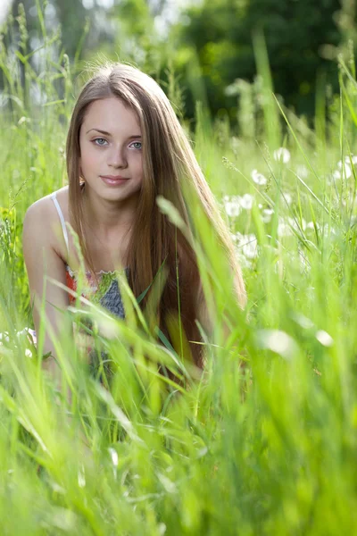 Ung vacker flicka lokalisering i gräset Stockfoto