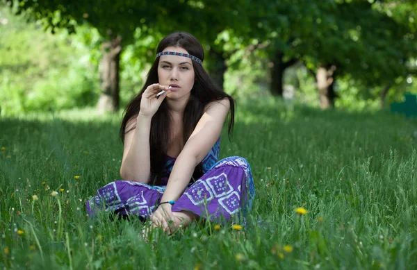 Hippy with cigarette sitting in the grass — Stock Photo, Image