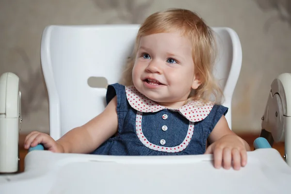 Malá dívka sedí u stolu a při pohledu vlevo Royalty Free Stock Fotografie