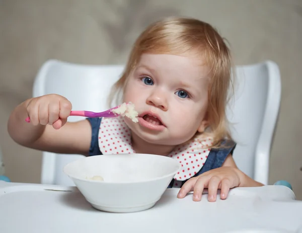 Kislány zabkását eszik. Stock Kép