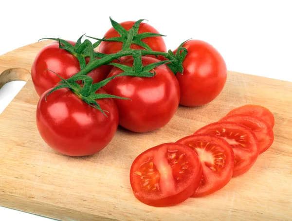 Fresh tomatoes and tomatoes slices on a hardboard — Stock Photo, Image