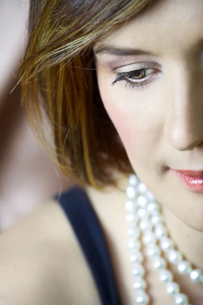 Belle jeune femme au maquillage naturel et aux cheveux bruns portant des perles — Photo