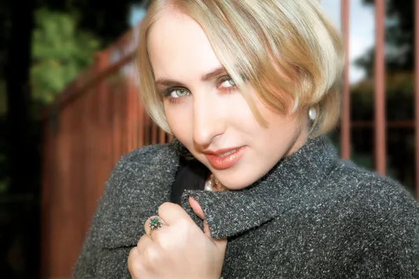 Mulher loira jovem em casaco de lã cinza e pérolas — Fotografia de Stock
