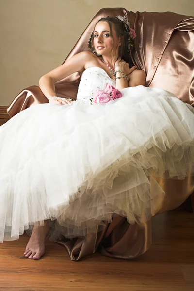 Невеста с длинными коричневыми волосами сидит в кресле — стоковое фото