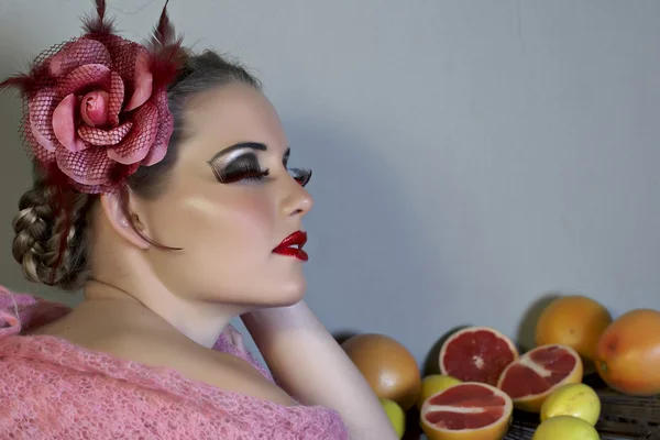 Blond kvinna med blomma i flätat hår och frukt — Stockfoto