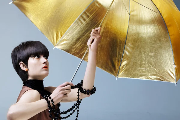 Frau mit goldenem Regenschirm. — Stockfoto