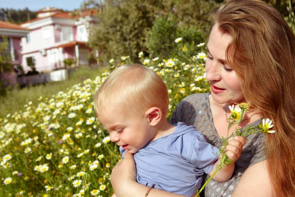 Grandmother and grandson in daisies field — Stock Photo, Image